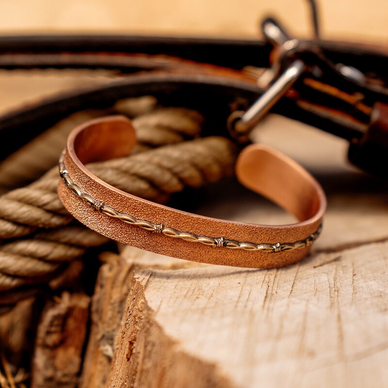 Copper cuff bracelet with silver barbed wire detail on a western set